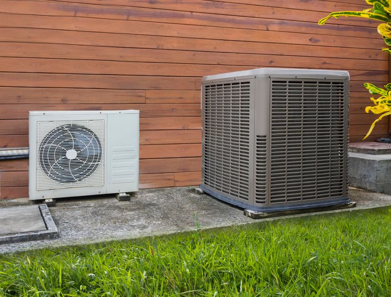 Ductless heat pump next to home heat pump outside residential home in Marlborough, MA.