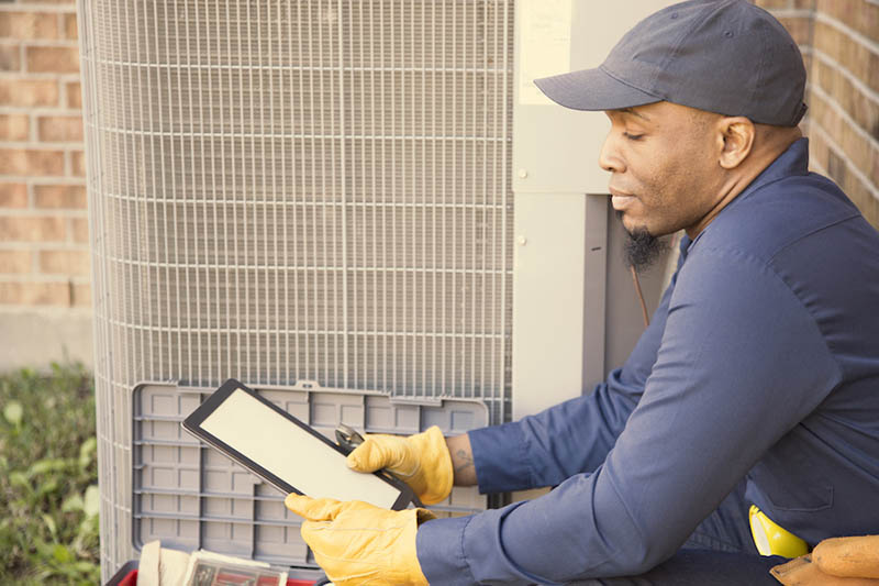 HVAC technician performing maintenance on AC due to environmental issues.