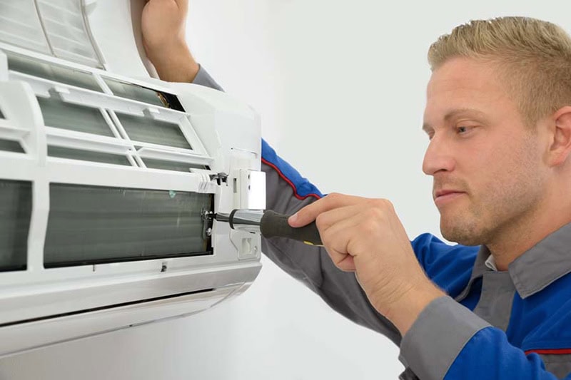 HVAC technician performing an AC tune-up on ductless mini split in Hudson, MA.