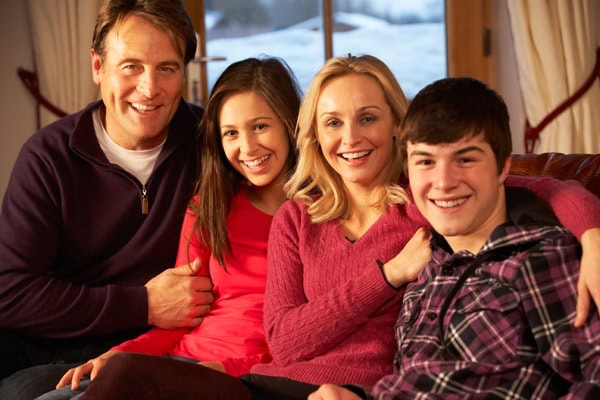 Portrait Of Family Relaxing On Sofa Together Smiling To Camera