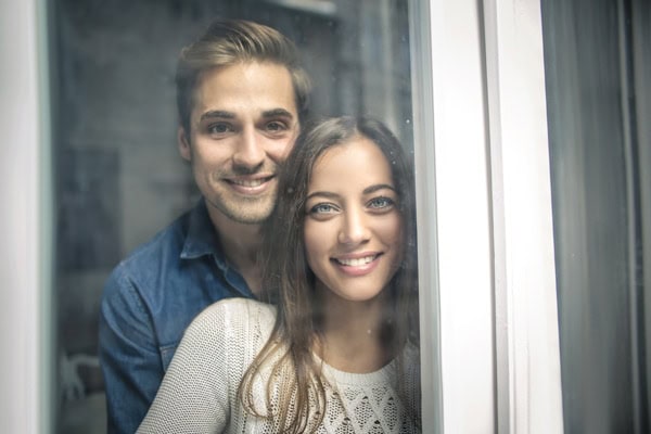 Happy young couple staring outside window to represent information on furnace pressure switches.