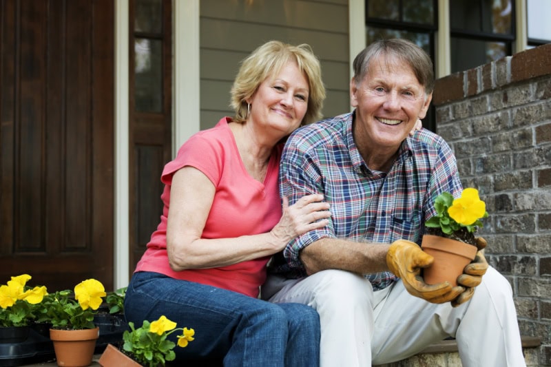 Married retired couple planting potted plants to represent when a heat pump instead of furnace makes sense.