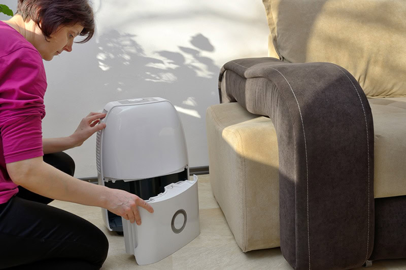 Female homeowner opening a portable humidifier.