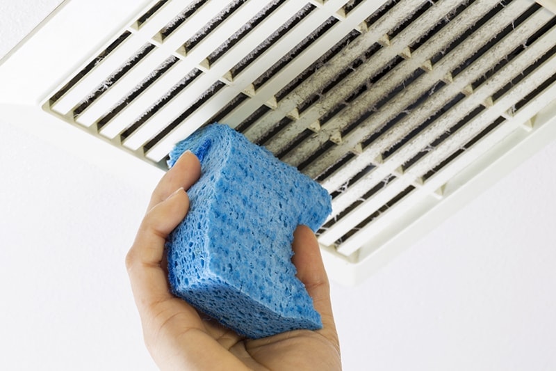 HVAC technician cleaning off build-up from vent before duct cleaning service in Sudbury, MA, home.