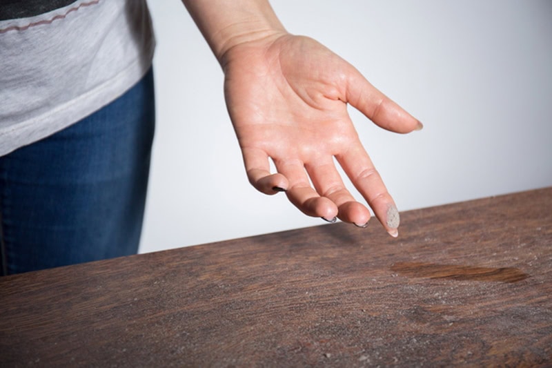 Homeowner wiping dust off of a table in her Hudson, MA, home.