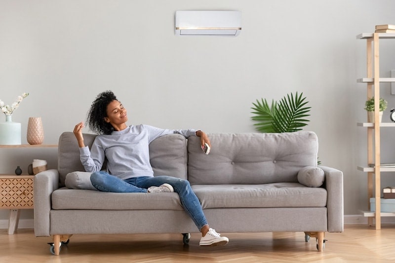 Young woman enjoying the cool breeze of her ductless system and the indoor air quality it provides.