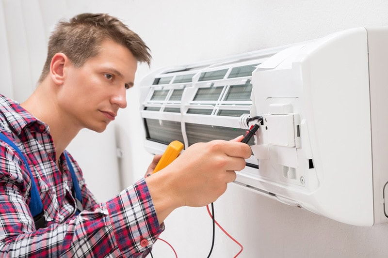 Technician performing an emergency HVAC repair on a ductless mini split.