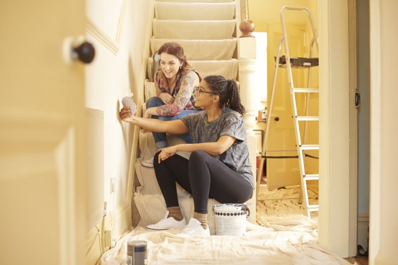 Two females reviewing different paint swatches to represent remodeling a home in fall or winter.