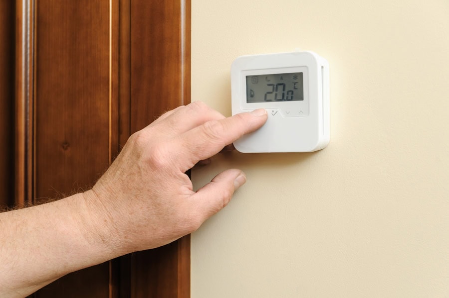 Homeowner adjusting thermostat in Hudson, MA, home.