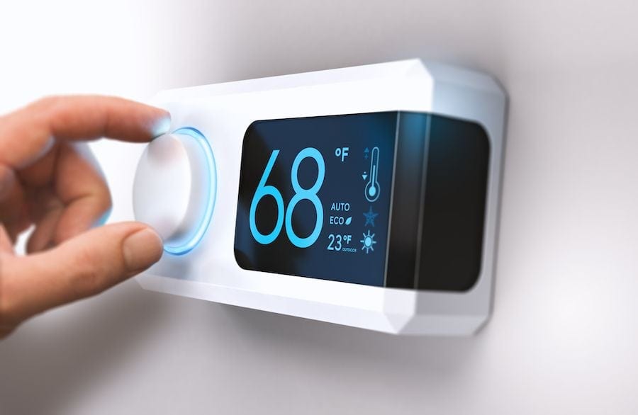 Male homeowner adjusting thermostat in Hudson, MA, home.