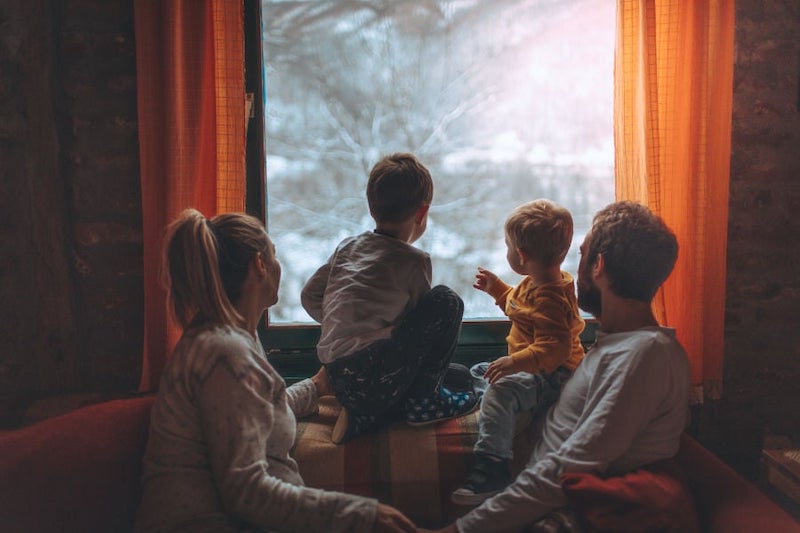 Family of four enjoying their indoor air quality while they stare out at the snowy winter outdoors.