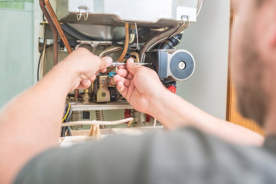 HVAC technician performing a furnace repair on pilot light in Hudson, MA, home.