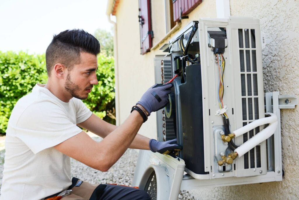 handsome young man electrician installing air conditioning in a client house
