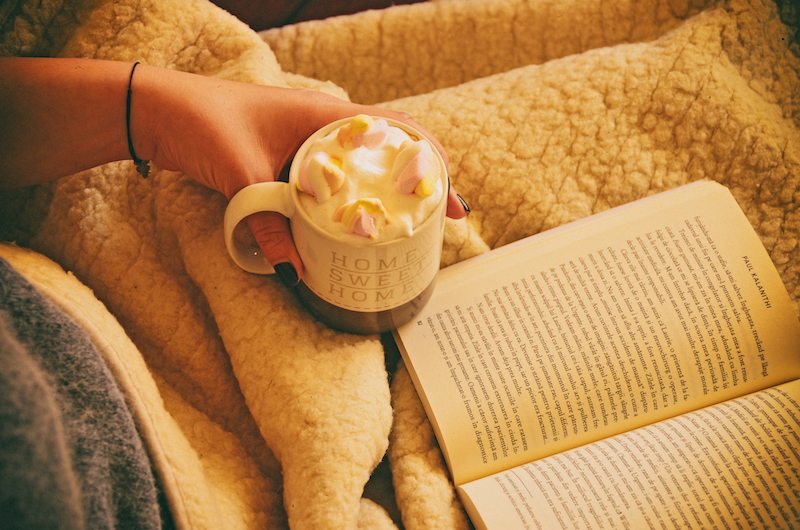 A person drinking hot chocolate while reading a book about furnace filters in Hudson