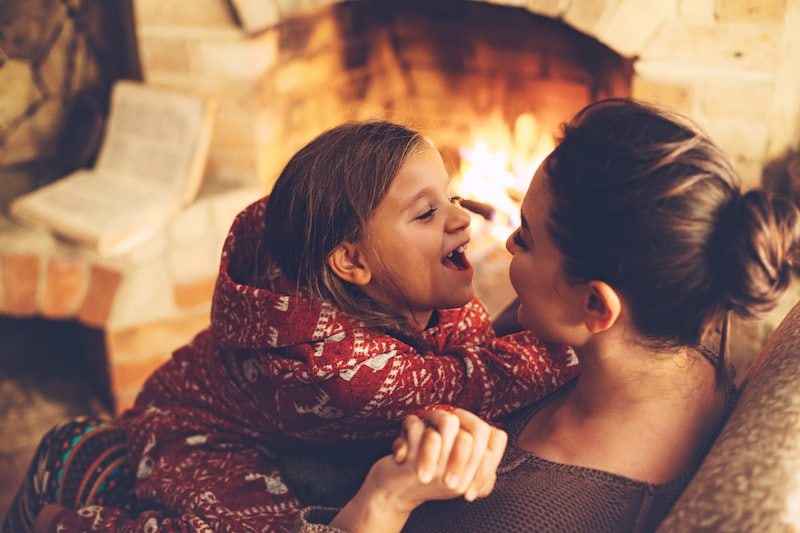 Mom and daughter sit by the fireplace